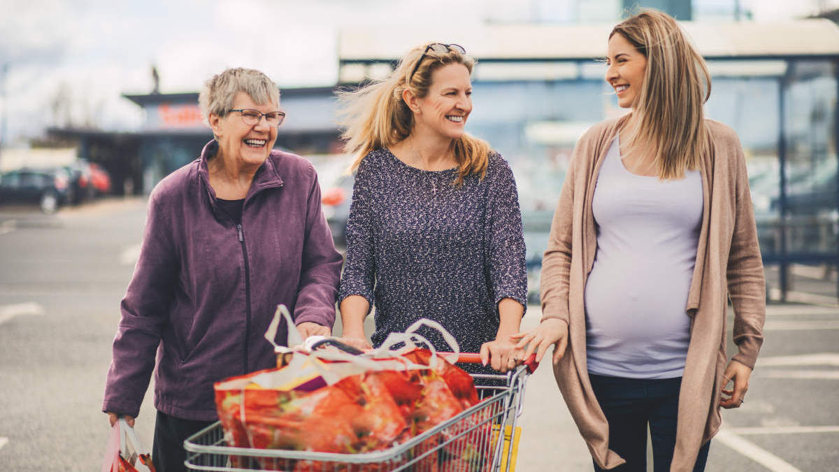 Three generation of woman are food shopping at the local grocery store, the youngest is heavily pregnant.